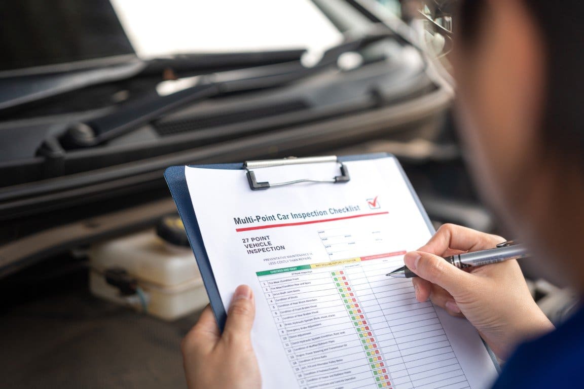 Multi-point vehicle inspection checklist being completed at an open engine bay