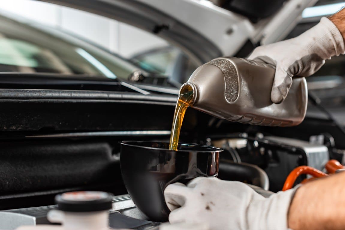 Fresh oil being poured into a vehicle engine during a fluid service