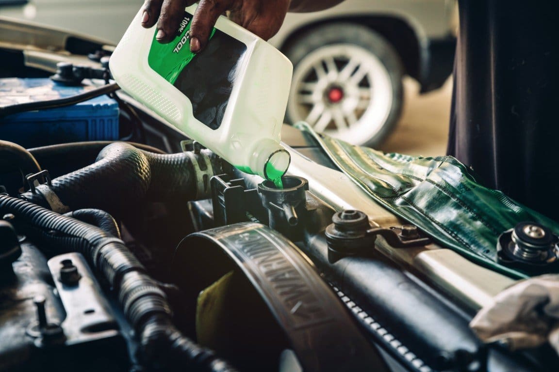 Technician adding coolant to a vehicle's cooling system reservoir