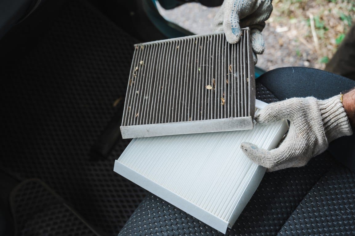 A dirty cabin air filter held beside a clean replacement