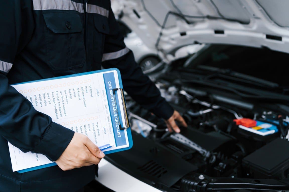 Technician carrying out a multi-point vehicle inspection in a repair shop