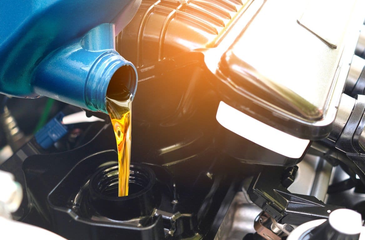 Fresh motor oil being poured into an engine during an oil change
