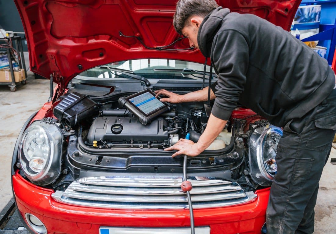 Two technicians working together on a vehicle inside a local auto repair shop